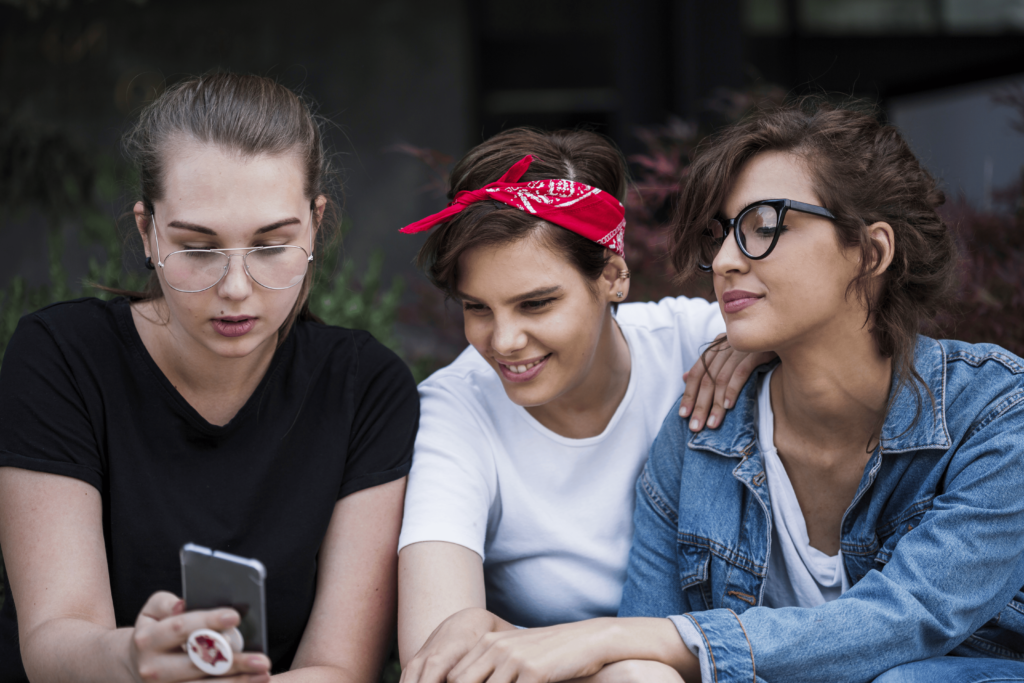 Friends Watching Pictures on their Smartphone in the Park